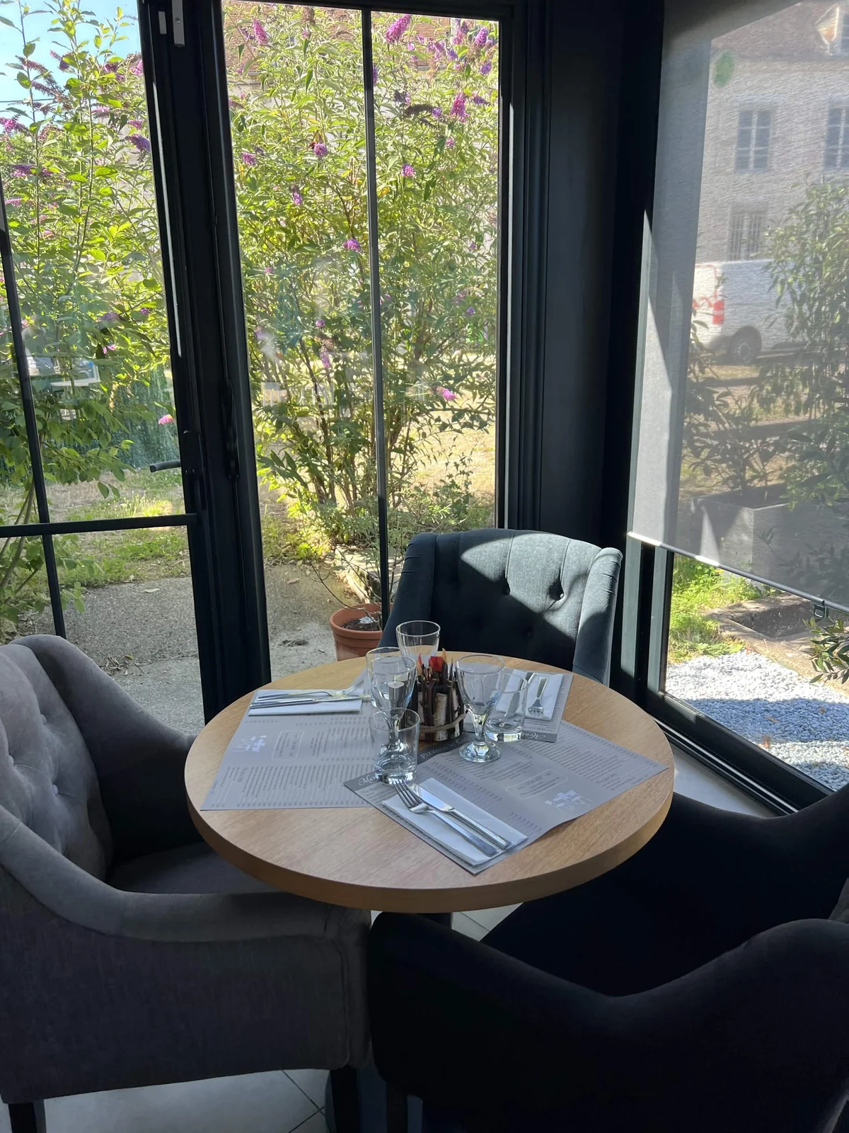 Table près des baies vitrées, vue sur le jardin, au Calypso